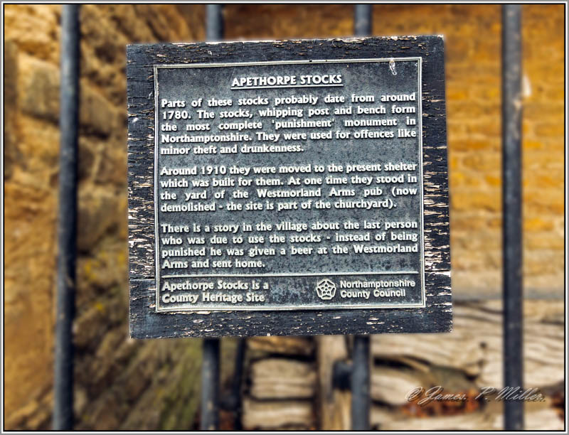 Sign on Apethorpe Village Stocks and Whipping Post, Apethorpe, Northamptonshire, England.